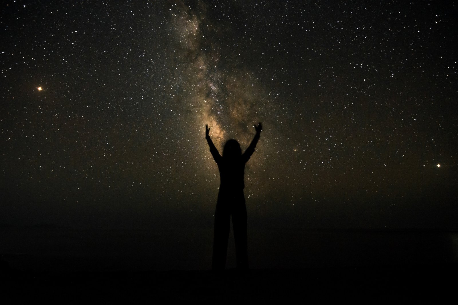 Person connecting with astrology for life guidance under starry night sky